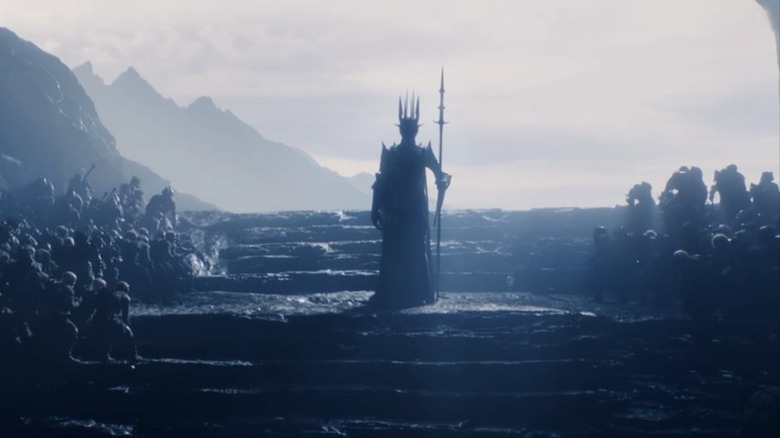 Sauron in a tall crown with a spear surrounded by Orcs