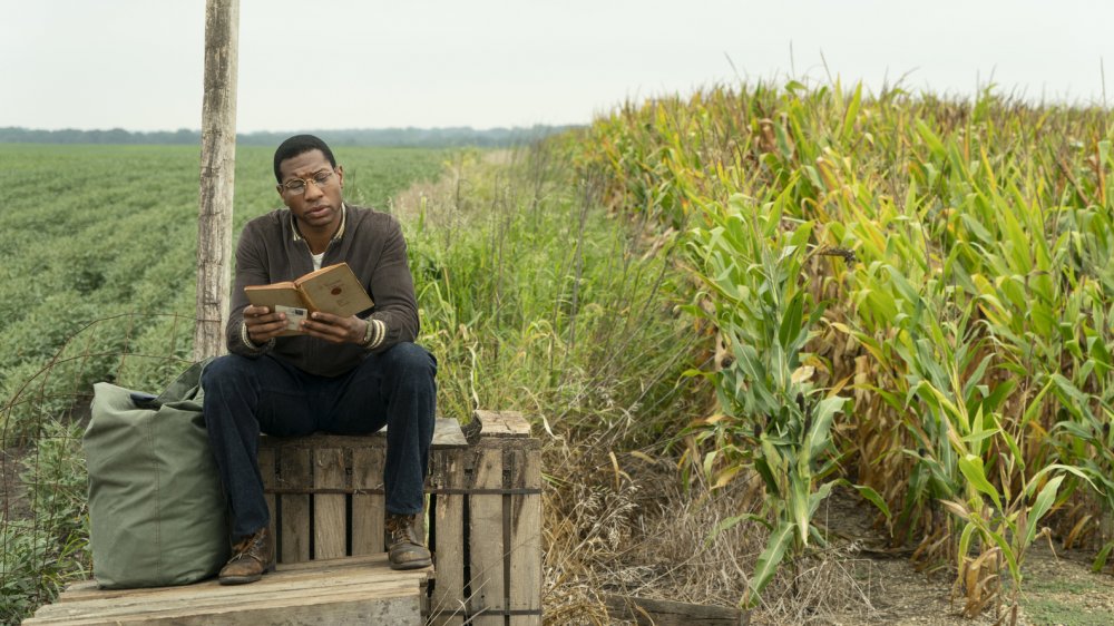 Atticus (Jonathan Majors) reads a book on Lovecraft Country