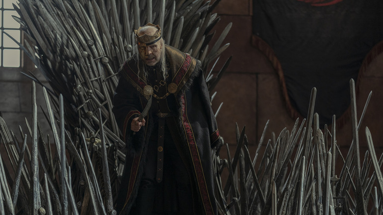 Viserys Targaryen (Paddy Considine) holding a knife next to the Iron Throne on House of the Dragon