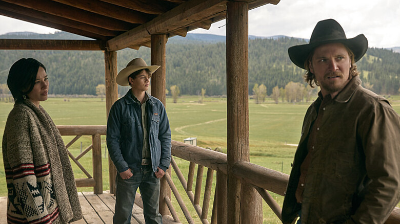 Monica, Tate, and Luke confer on a porch on "Yellowstone"