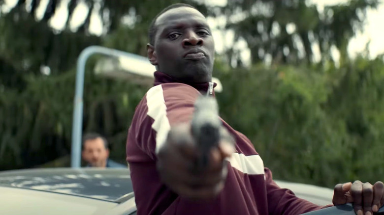 Assane Diop pointing a gun