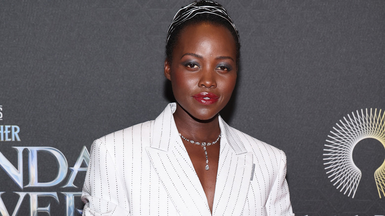 Lupita Nyong'o wearing a white suit and diamond necklace