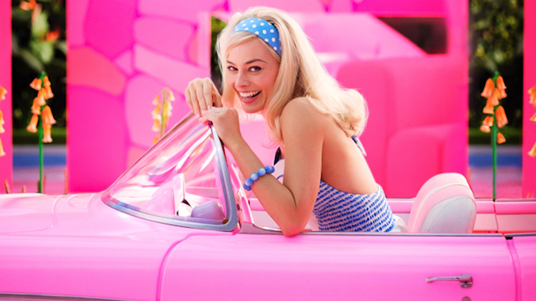 Margot Robbie sitting in pink car