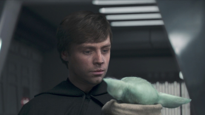 Young Luke holding Grogu