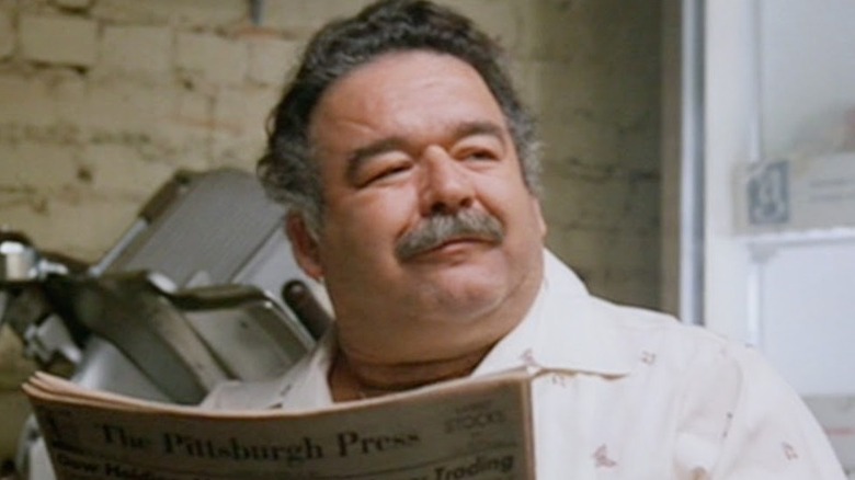 Flashdance Ron Karabatsos smiles while reading a newspaper