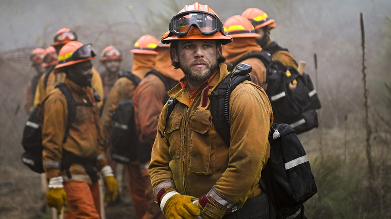 Bode Donovan looking serious, standing in front of other firefighters