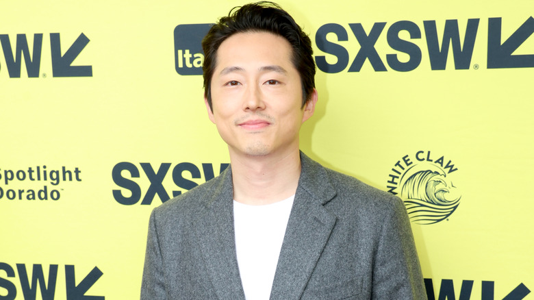 Steven Yeun smiling on red carpet