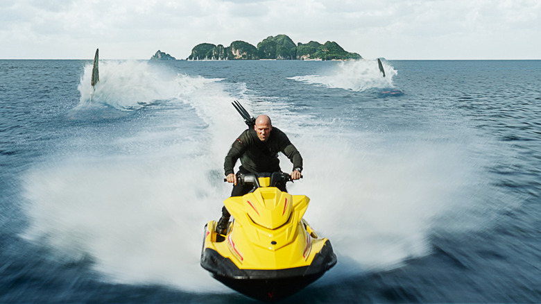 Jason Statham riding jet ski escaping sharks