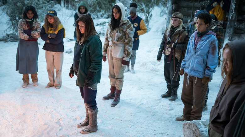 Teen Yellowjackets stand in snow 