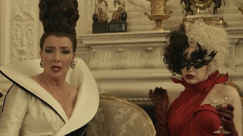 Cruella De Vil and the Baroness stand in front of a mantle looking shocked