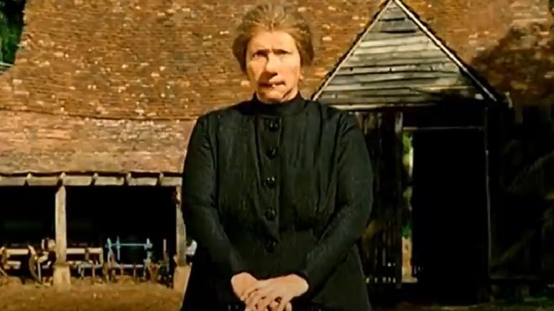 Nanny McPhee stands in front of a rundown house