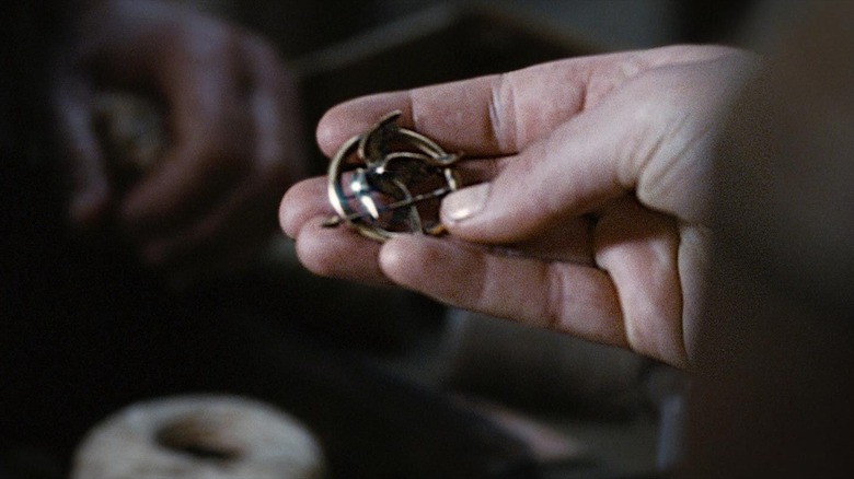 Katniss holds her Mockingjay pin