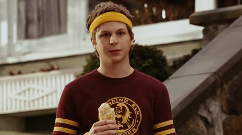 Michael Cera in jogging attire holds a hot pocket