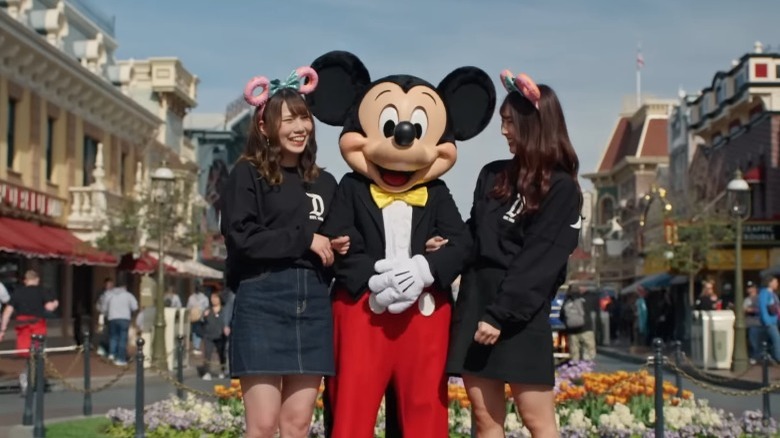 Person dressed as Mickey Mouse standing between two girls