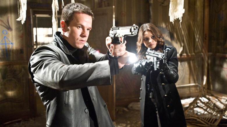 Mark Wahlberg and Mila Kunis pointing guns at an enemy