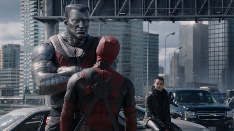 Colassus standing in front of Deadpool with arms crossed on highway