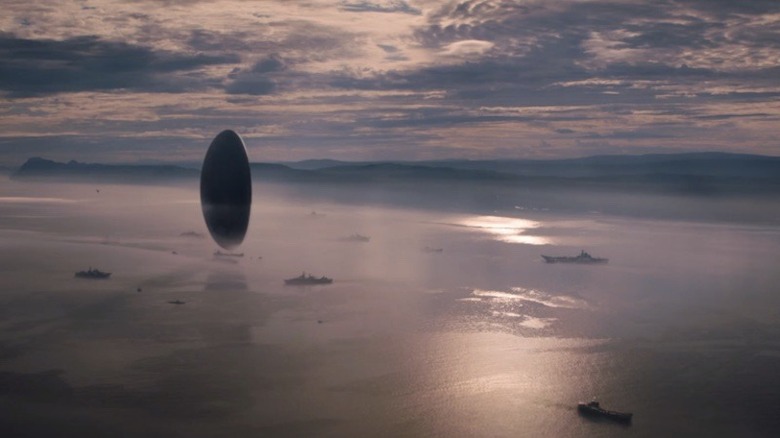 Oblong spacecraft hovering over ocean 