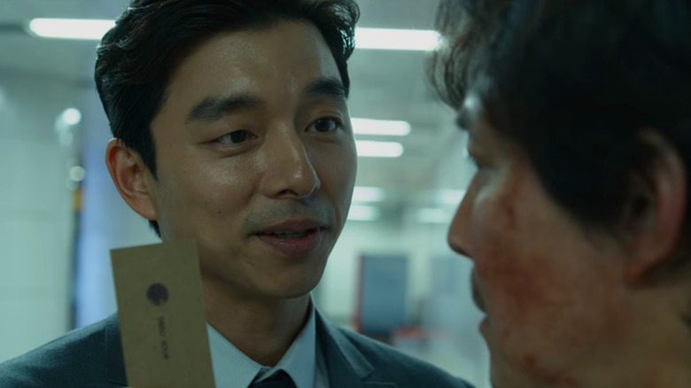 The Salesman offering a card to Seong Gi-hun in "Squid Game" (2021)