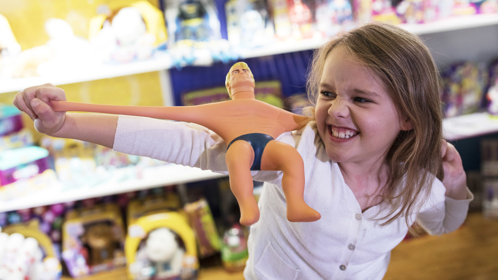 A young girl plays with a Stretch Armstrong toy