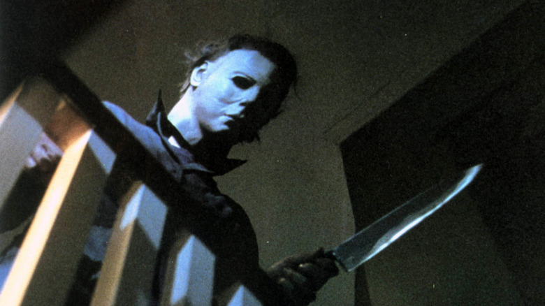 Michael Myers leans over bannister with knife