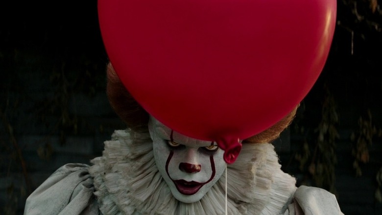 Pennywise stands behind a balloon