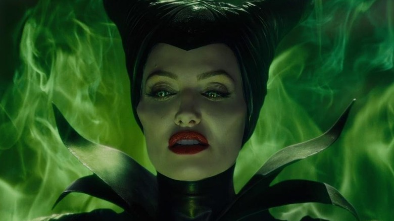 Maleficent stands near green flames