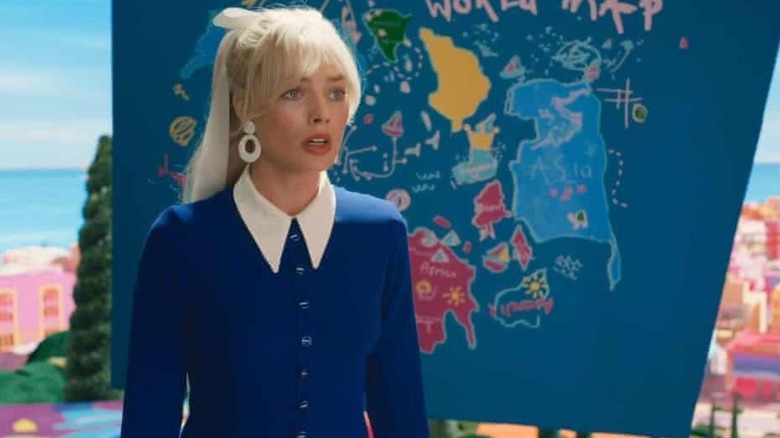 Barbie stands near a world map