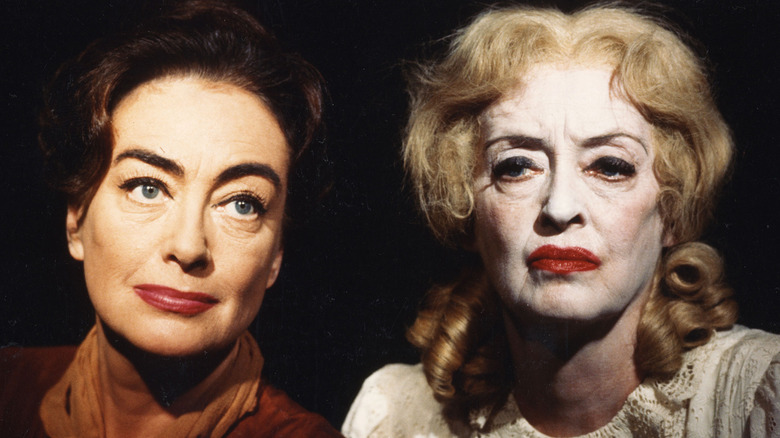 Joan Crawford looks up and Bette Davis stares ahead