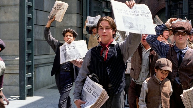 The Newsies hold up newspapers