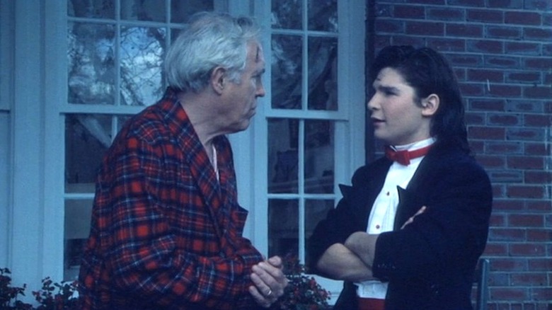 Jason Robards as Coleman and Corey Feldman as Bobby standing outside a window in "Dream a Little Dream."