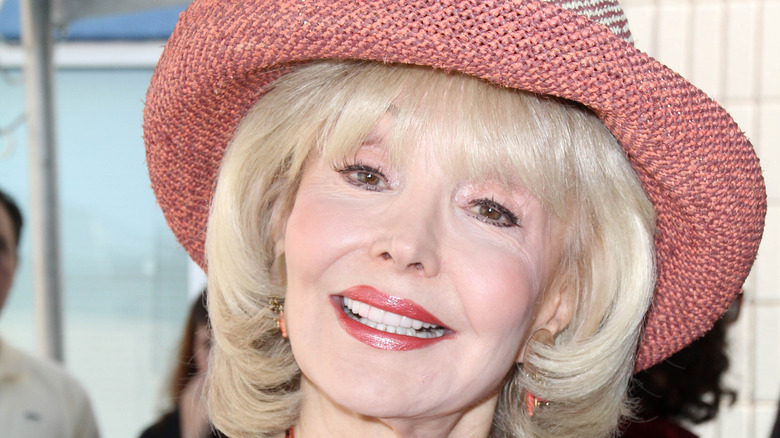 Francine York, wearing a hat, tilts her head while smiling