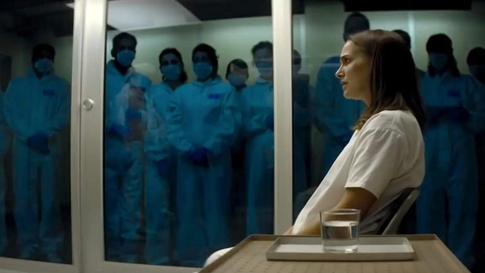 Natalie Portman as Lena sitting in a glass cell surrounded by medical professionals in scrubs and face masks in "Annihilation"