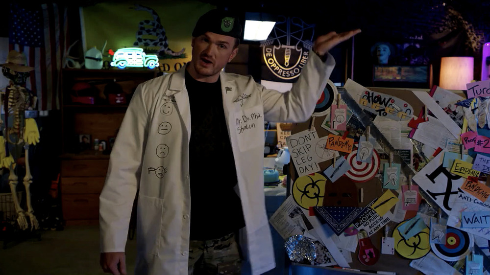 man in Green Beret and lab coat gestures at messy bulletin board