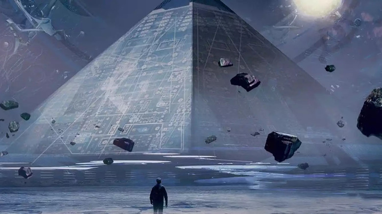 Someone stands in front of a strange pyramid