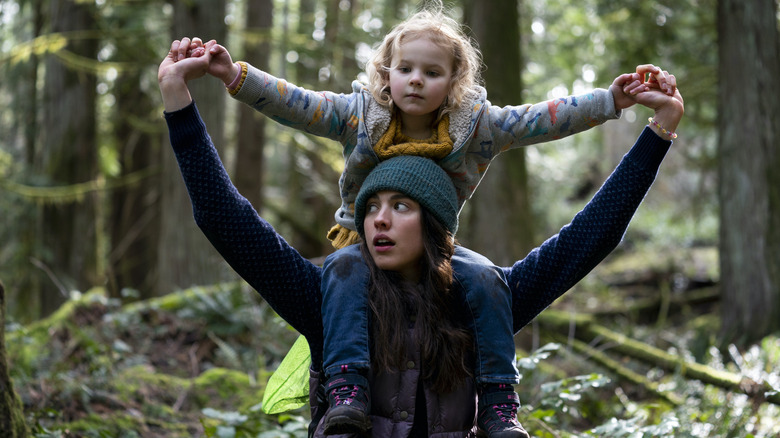 Maddy sits on Alex's shoulders in the woods in Maid