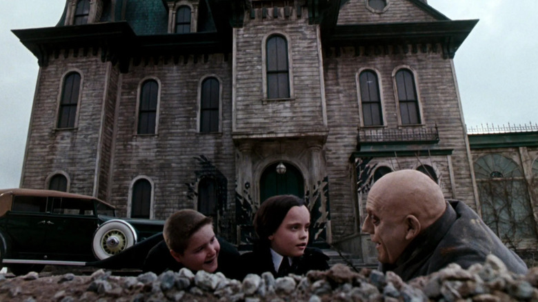 Addams Family in front of their mansion