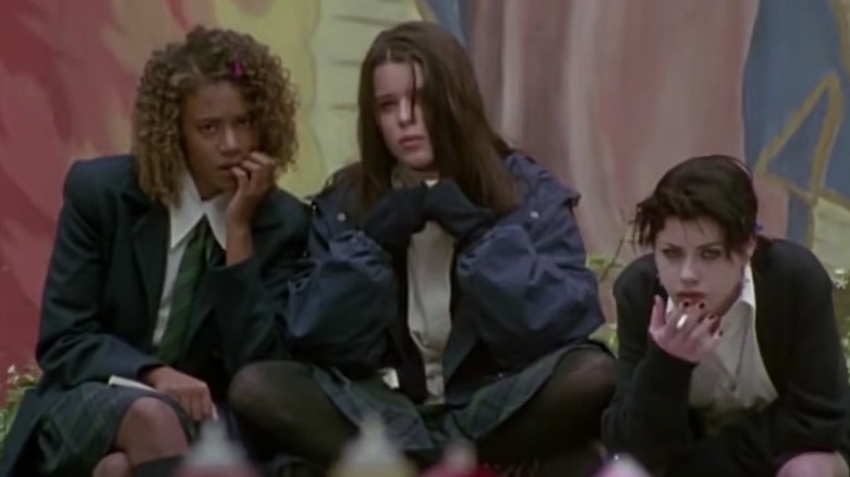 Rachel True, Neve Campbell, Fairuza Balk sit outside in front of mural