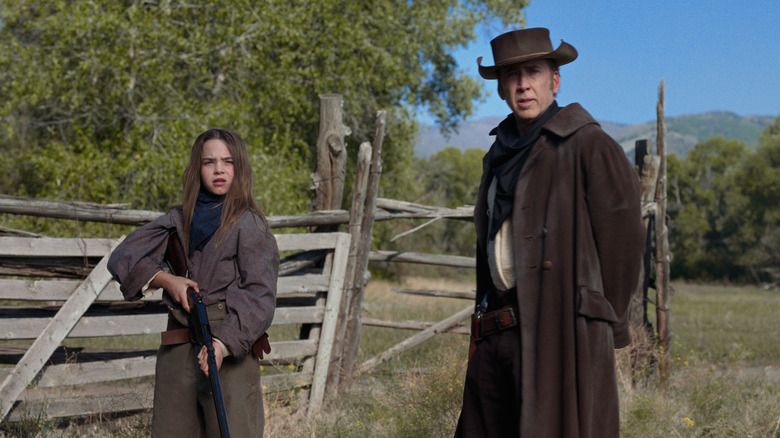 Ryan Kiera Armstrong and Nicolas Cage standing by fence in The Old Way