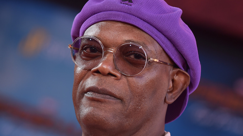 Samuel l. Jackson at event smiling wearing glasses and purple hat