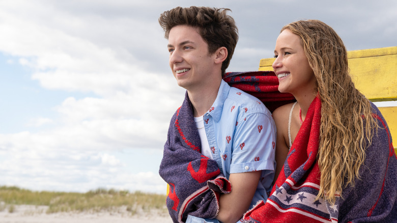 Percy and Maddie sitting on the beach and sharing a beach towel 