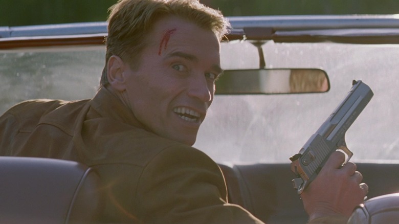 Jack Slater smiles holding gun