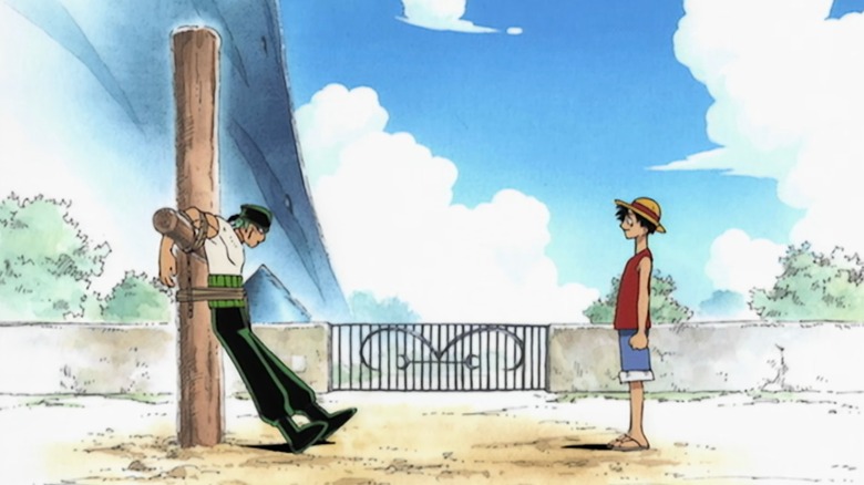 Luffy looks at Zoro chained to a post