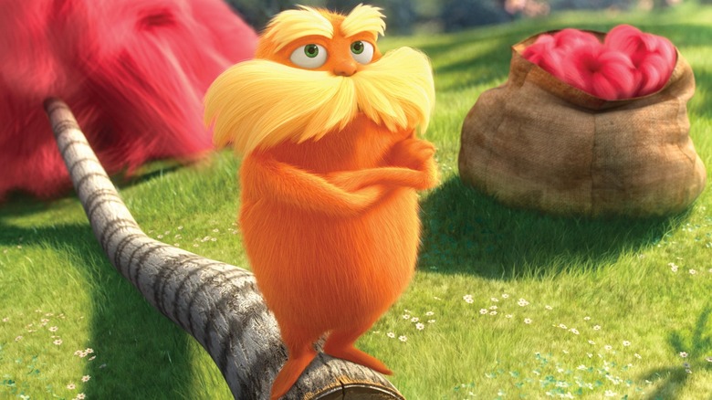 The Lorax stands cross-armed on a chopped down tree