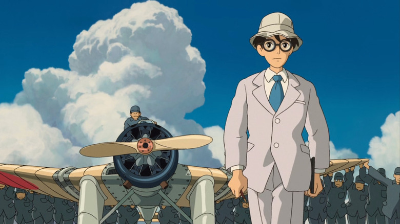 Jiro with men pushing airplane behind him 