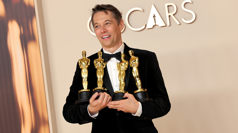 Sean Baker holding a bunch of Oscars