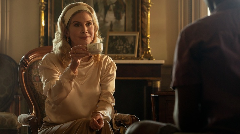 Carla wearing a white blouse and holding a teacup