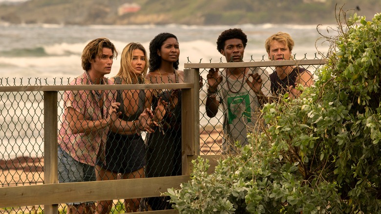 John B, Sarah, Cleo, Pope, and JJ standing behind fence