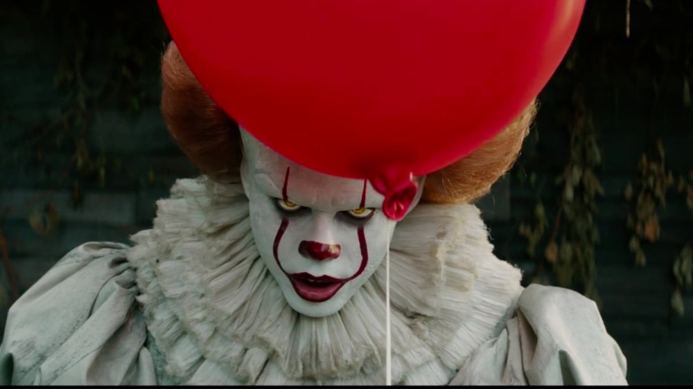 Bill Skarsgard holds a red balloon as Pennywise in It