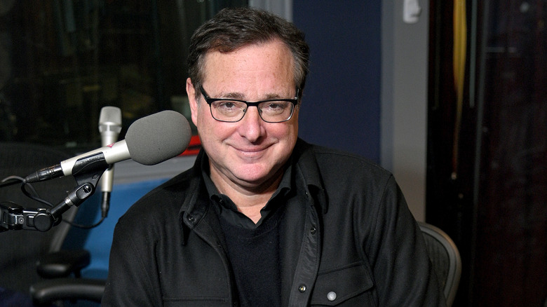 Bob Saget sitting near microphone