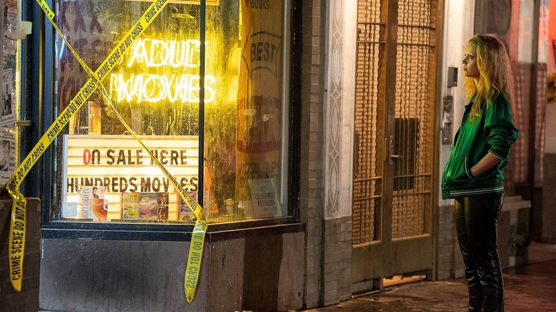 Maxine Minx standing outside a tattered adult video store in MaXXXine (2024)